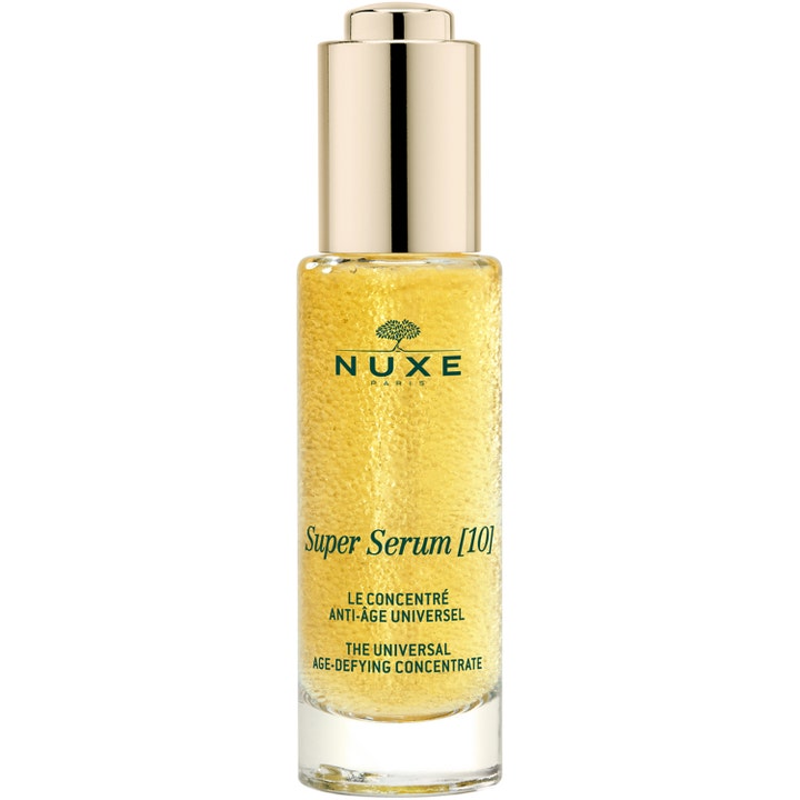 Nuxe Super Serum [10] 30 ml silottava seerumi kirkkaassa lasipullossa, jossa on kultaisia mikropisaroita.