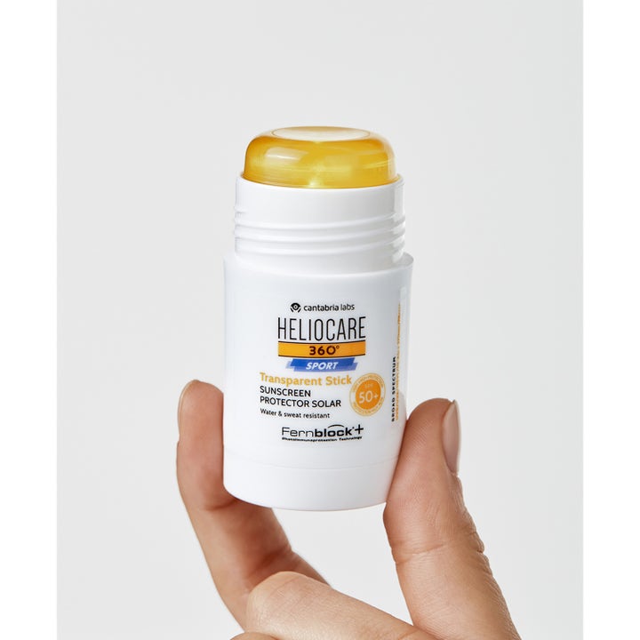 Heliocare Sport Stick SPF 50+ 25 g aurinkosuojapuikko kädessä, valkoinen pakkaus ja läpinäkyvä keltainen koostumus