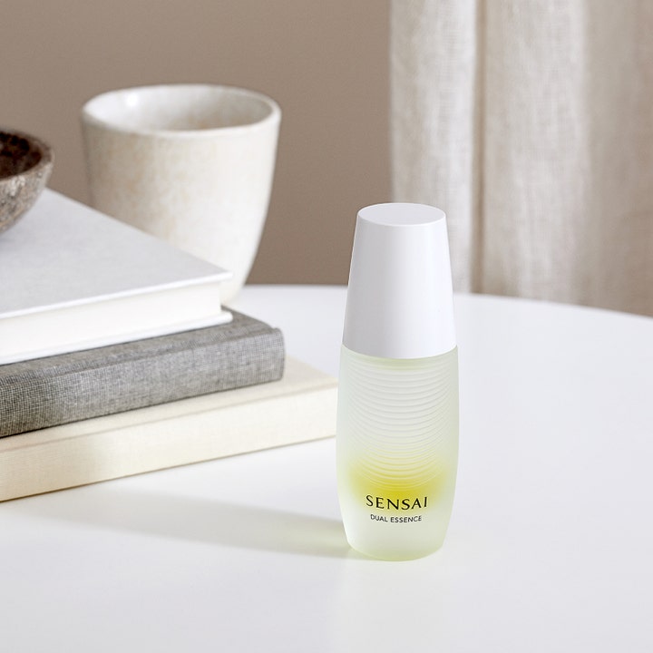 Sensai Dual Essence 30 ml heleyttävä hoitoneste huurretussa lasipullossa aseteltuna valkoiselle pöydälle.