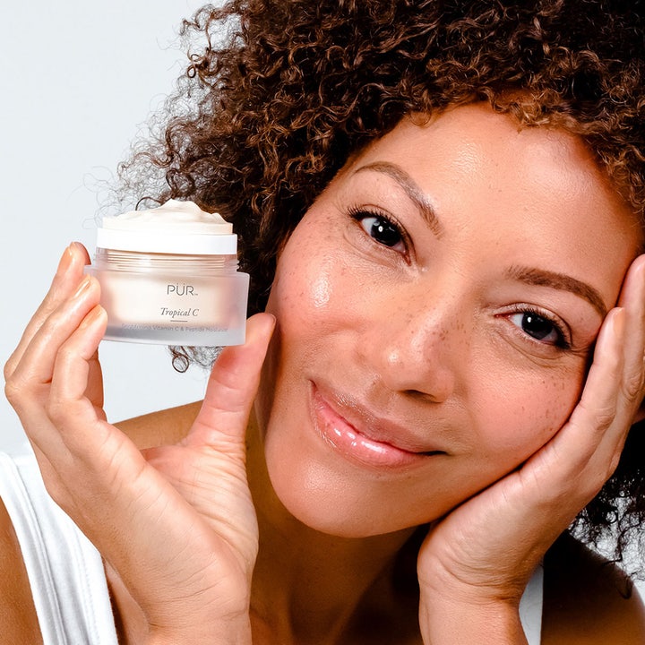 PÜR Tropical C Brightening Vitamin C & Peptide Moisturizer 50 ml kirkastava kasvovoide nainen pitelee purkkia iho hehkuen.