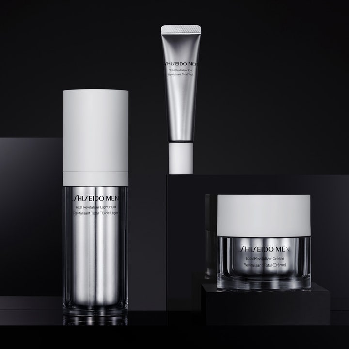 Shiseido Men Total Revitalizer Liquid Fluid 70 ml elvyttävä kasvovoide ja muita tuotteita mustalla taustalla.
