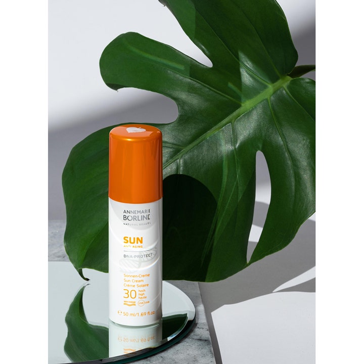 Annemarie Börlind Sun DNA Protect SPF 30 50 ml anti-aging aurinkovoide oranssikorkkisessa pullossa suuren peikonlehden edessä.