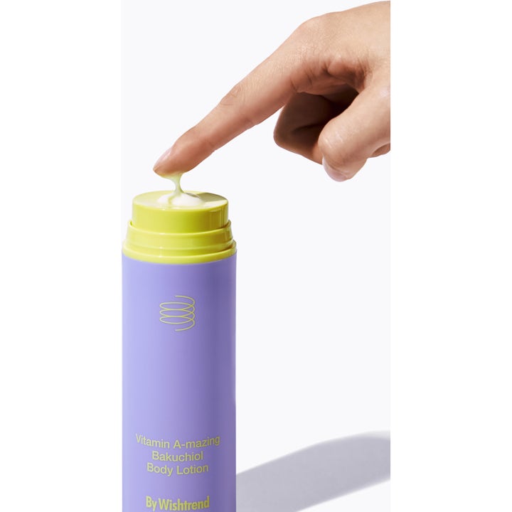 By Wishtrend Vitamin A-mazing Bakuchiol Body Lotion 150 g silottava vartalovoide, sormi ja keltaista voidetta pumpun päällä.
