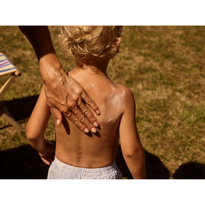 Rudolph Care Sun Lotion Kids SPF30 200 ml aurinkorasva lapsille. Käsi levittää suojaavaa voidetta lapsen selkään.