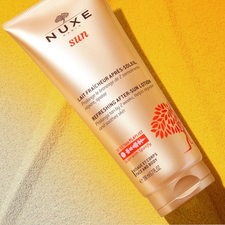 Nuxe Sun Refreshing After Sun Lotion 200 ml pidentää rusketusta ja kosteuttaa ihoa pronssisessa tuubissa hiekalla