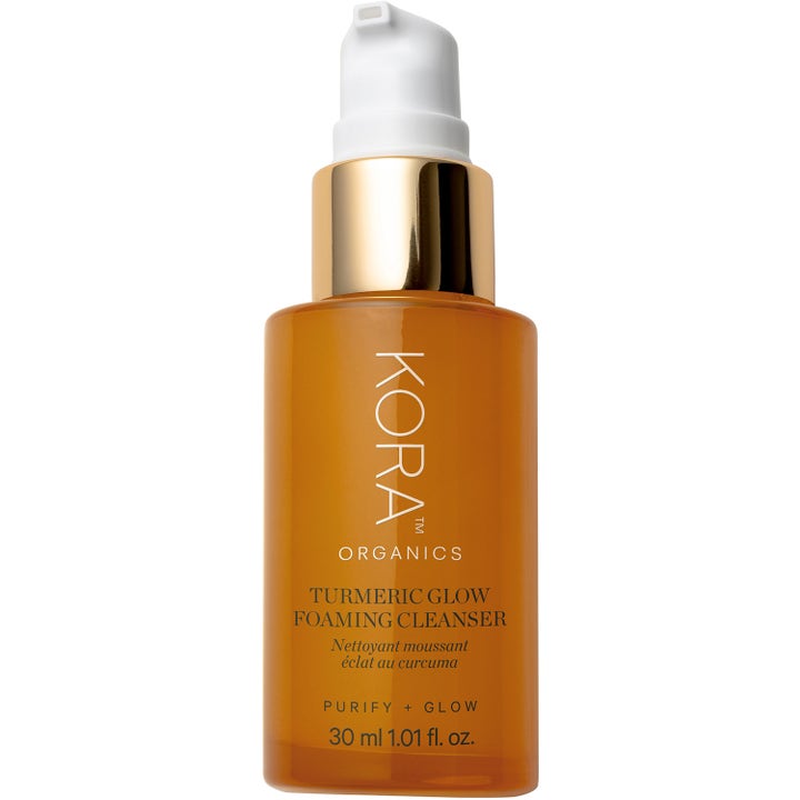 Kora Organics Turmeric Glow Foaming Cleanser 30 ml heleyttävä puhdistustuote oranssissa pullossa kultaisella kauluksella.
