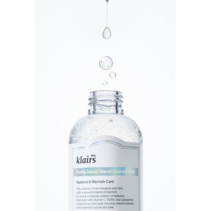 Klairs Freshly Juiced Vitamin Essence Toner 180 ml kirkastava kasvovesi ja pullon yllä leijuvia seerumipisaroita.