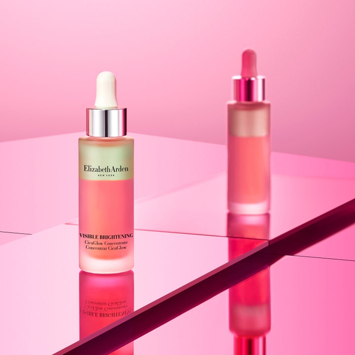 Elizabeth Arden Visible Brightening Cica Glow 30 ml kirkastava seerumi lasisessa pipettipullossa vaaleanpunaisella pinnalla.