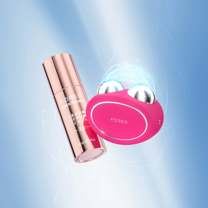 FOREO BEAR 2 Fuchsia 1 kpl ihon kiinteytystä parantava mikrovirtalaite ja 30 ml seerumipullo sinisellä taustalla.