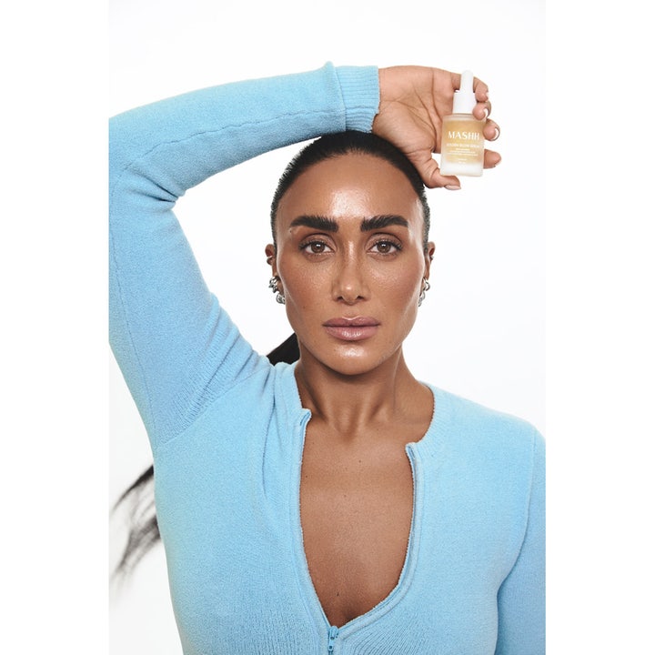 MASHH Golden Glow Serum 30 ml heleyttävä kasvoseerumi mallin kädessä luomassa iholle tervettä hehkua.