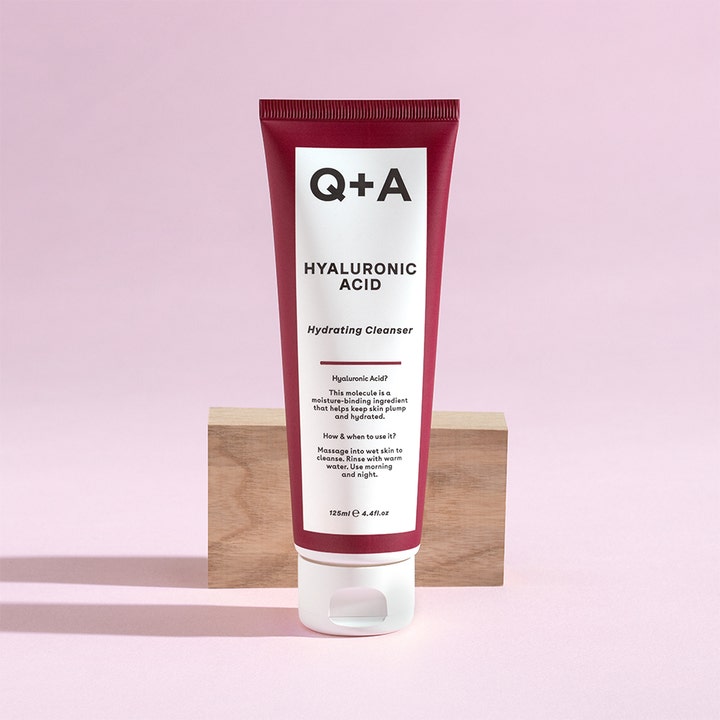 Q+A Hyaluronic Acid Gel Cleanser 125 ml kosteuttava puhdistusgeeli punaviininpunaisessa tuubissa puupalikan päällä