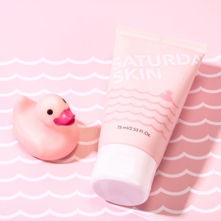 Saturday Skin Rub-a-Dub Refining Peel Gel 75 ml kirkastava kuorintageeli vaaleanpunaisessa tuubissa kylpyankan vieressä