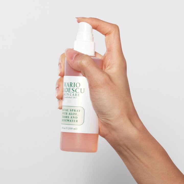 Mario Badescu Facial Spray Aloe, Herbs & Rosewater 118 ml kosteuttava kasvosuihke vaaleanpunaisessa pullossa kädessä.