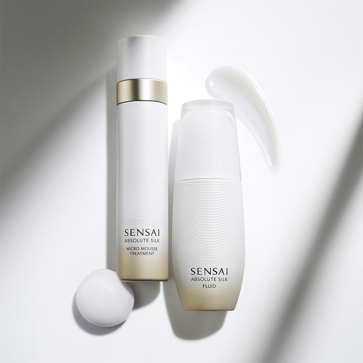 Sensai Absolute Silk Fluid 80 ml kosteuttava päivävoide valkoisessa pullossa ja kevyt voidemainen koostumus.