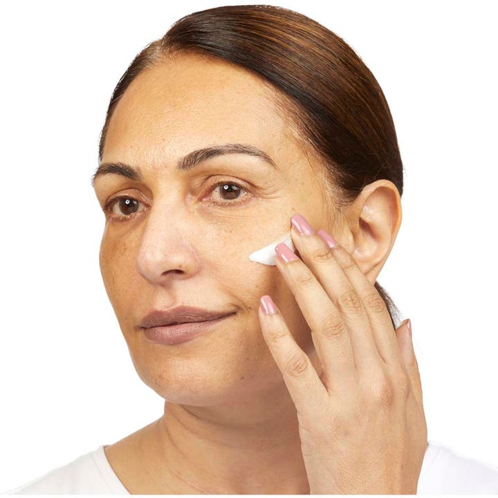 No7 Restore & Renew Multi Action Night Cream 50 ml nattkräm jota nainen levittää sormin poskensa iholle.