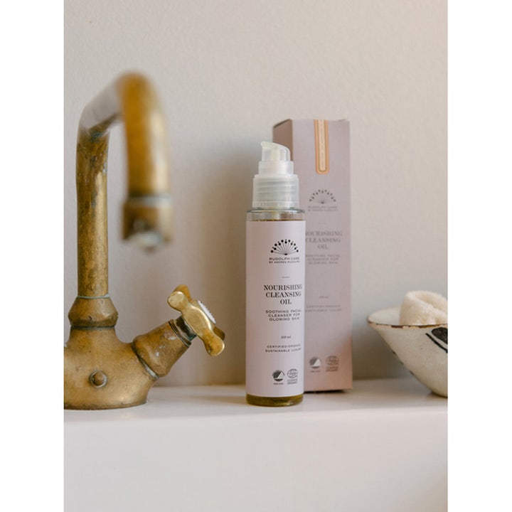 Rudolph Care Nourishing Cleansing Oil 100 ml puhdistusöljy ja pakkaus messinkisen hanan vieressä