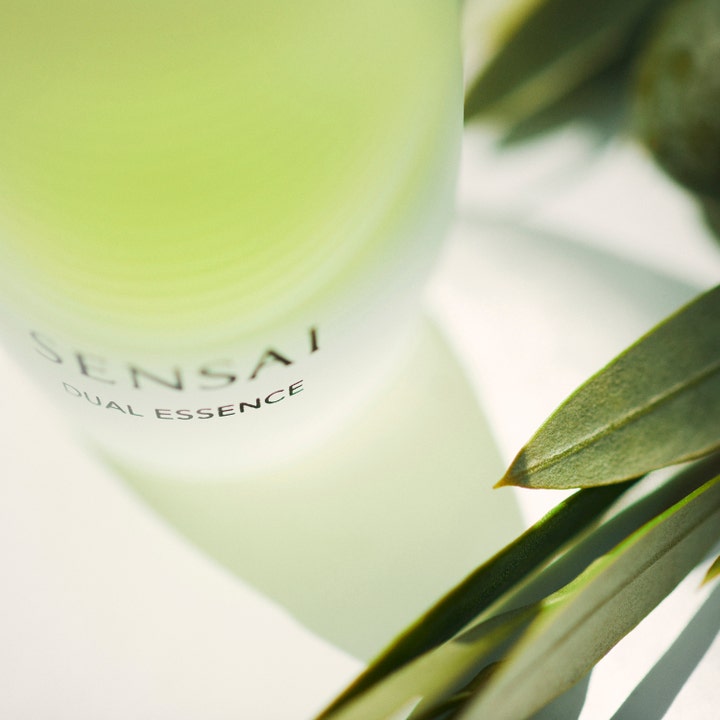 Sensai Dual Essence 30 ml kosteuttava hoitoneste huurteisessa lasipullossa vihreiden lehtien ympäröimänä.