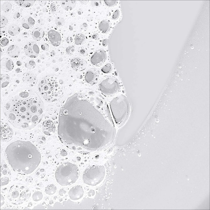 Dermalogica Conditioning Body Wash 295 ml pehmentävä suihkugeeli ja ilmavaa valkoista saippuakuplaa.