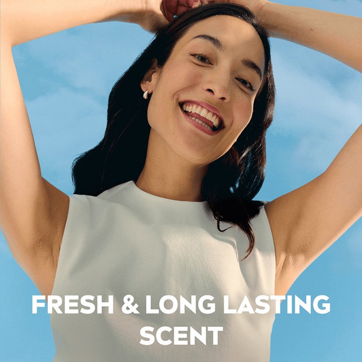 NIVEA Deo Rollon Dry Comfort 50 ml antaa raikkaan tuoksun hymyilevälle naiselle sinistä taivasta vasten.