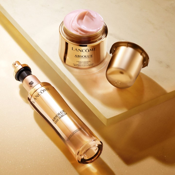 Lancôme Absolue Serum Star 30 ml kirkastava seerumi kultaisessa pullossa ja kasvovoide vaaleanpunaisella koostumuksella.