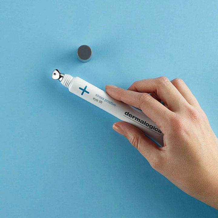 Dermalogica Stress Positive Eye Lift 25 ml virkistävä silmänympärysvoide kädessä viilentävällä metalliapplikaattorilla.
