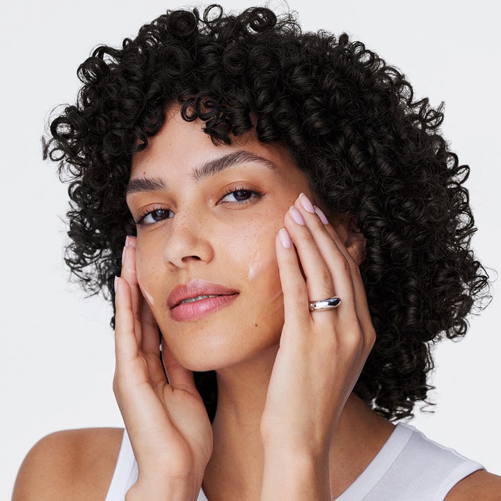 Clinique Moisture Surge 100H 50 ml kosteuttava kasvovoide jota nainen levittää iholleen geelimäisen hehkun saamiseksi.