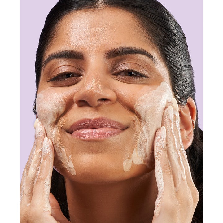 Exuviance 3-in-1 Clarifying Cleanser 212 ml kirkastava puhdistustuote, jota nainen levittää vaahtona kasvoilleen.
