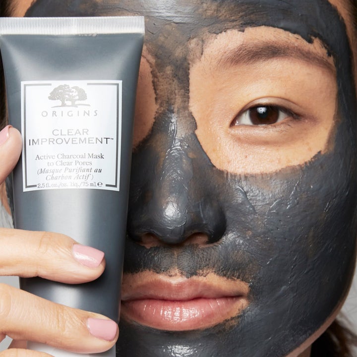 Origins Clear Improvement Active Charcoal Mask 75 ml syväpuhdistava kasvonaamio harmaassa tuubissa ja levitettynä kasvoille.