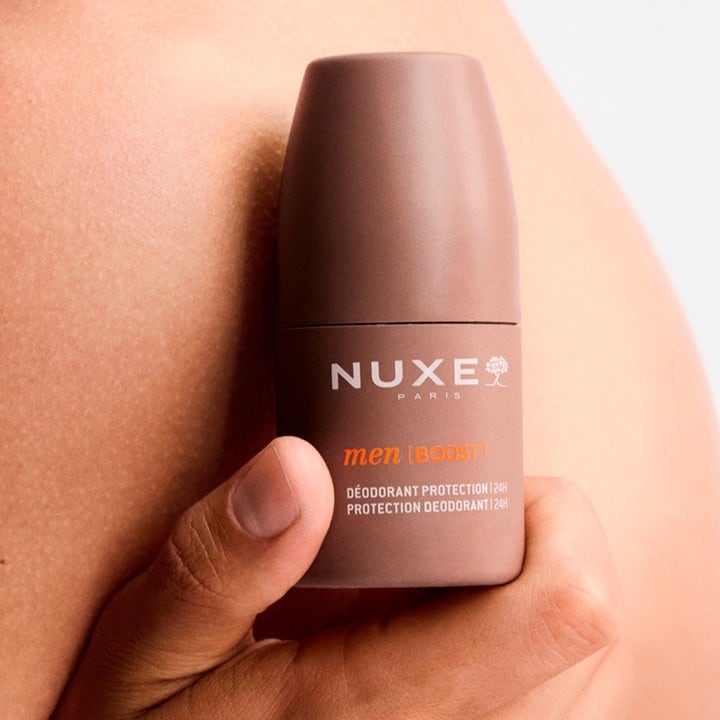 Nuxe Men 24Hr Protect Deo 50 ml suojaava roll-on-deodorantti ruskeassa pakkauksessa pidettynä ihoa vasten