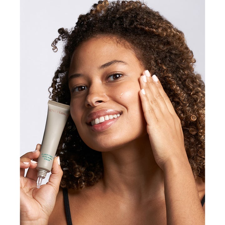 Exuviance Clarifying and Renewing Serum 30 ml kirkastava seerumi nainen pitelee tuubia ja levittää tuotetta iholle.