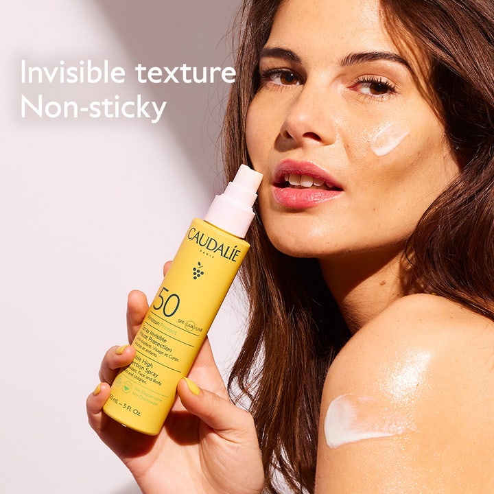 Caudalie Vinosun High Protection Spray SPF50 150 ml aurinkosuoja ja nainen levittämässä voidetta kasvoille.