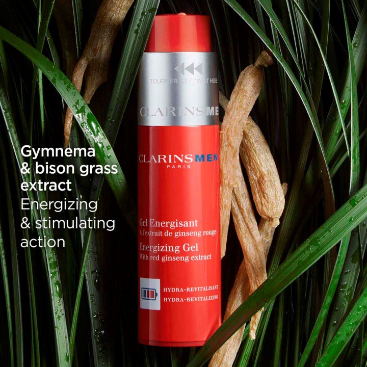 Clarins Clarins Men Energizing Gel 50 ml virkistävä kasvogeeli punaisessa pullossa vihreän ruohon ja juurten keskellä.