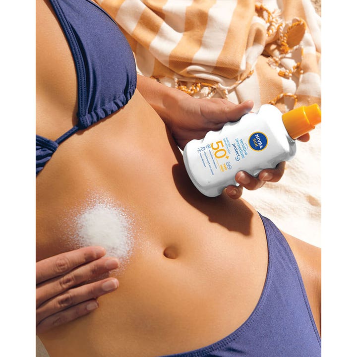 NIVEA Sensitive Immediate Protect 200 ml rauhoittava aurinkovoide jota henkilö levittää vatsan iholle rannalla.