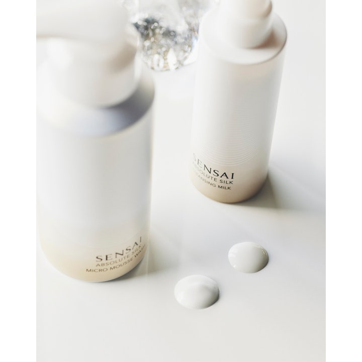 Sensai Absolute Silk Micro Mousse Wash 180 ml ihoa kirkastava puhdistusvaahto valkoisessa pullossa ja kaksi vaahtopisaraa
