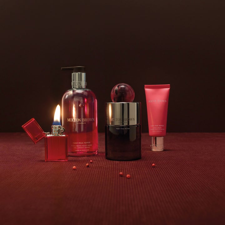 Molton Brown Fiery Pink Pepper Hand Cream 40 ml kosteuttava käsivoide pinkissä tuubissa punaisen sytyttimen rinnalla.