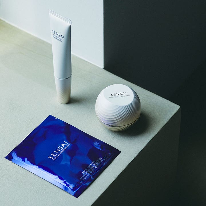Sensai Total Eye Treatment 35 ml silmänympäryshoito valkoisessa tuubissa ja purkissa sekä sininen silmänaamio
