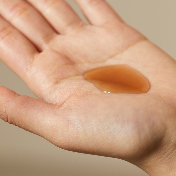 Hyggee Natural Repair Serum 120 ml korjaava seerumi kämmenellä näkyvänä meripihkanvärisenä ja ihoa uudistavana nesteenä.