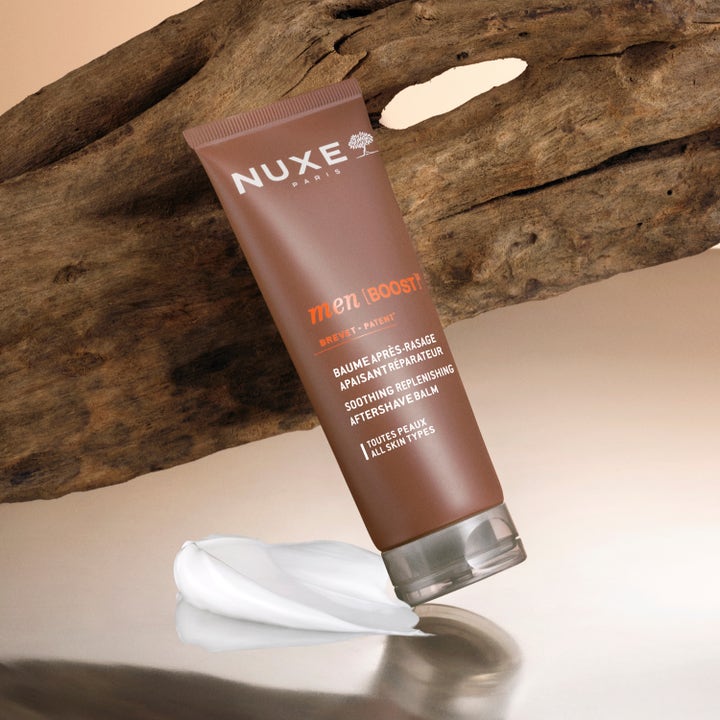 Nuxe Men Soothing Replenishing Aftershave Balm 75 ml rauhoittava ja korjaava voide ruskeassa tuubissa puuta vasten.