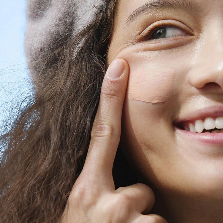 Dermalogica AGE smart Skinperfect Primer SPF30 tasoittava aurinkosuoja luo tasaisen sävyn naisen poskelle.