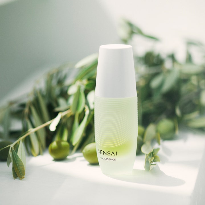 Sensai Dual Essence 30 ml kosteuttava essence valkoisella korkilla oliivinoksien ympäröimänä.
