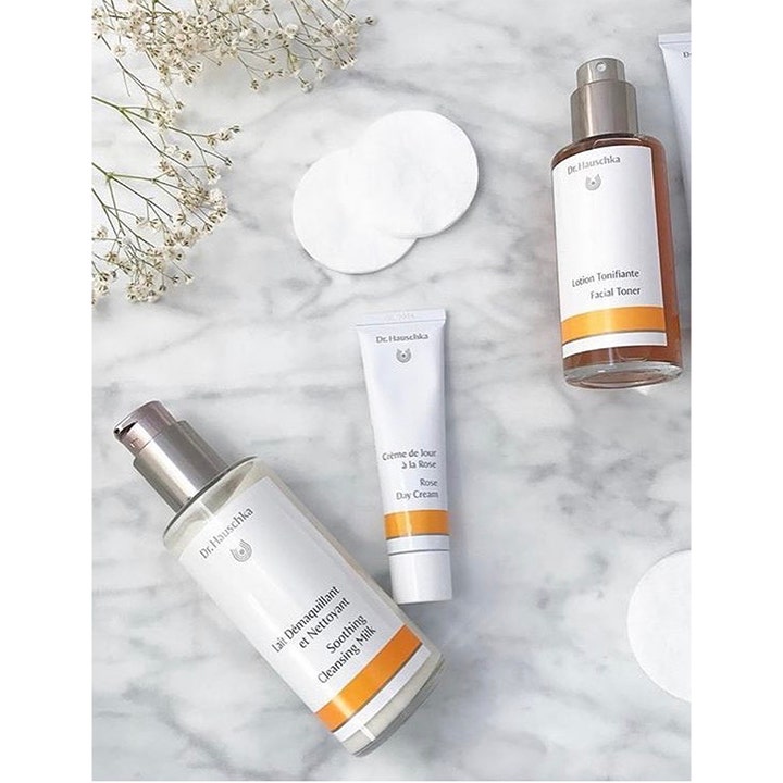 Dr. Hauschka Rose Day Cream 30 ml suojaava päivävoide tuubissa marmorilla kukkien ja muiden tuotteiden kera.