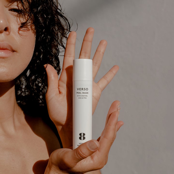 Verso N°8 Peel Mask 50 ml kuoriva kasvonaamio valkoisessa pumppupullossa naisen käsissä.