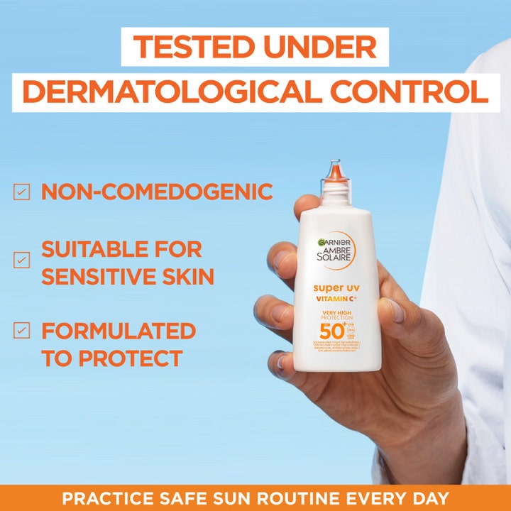 Garnier Ambre Solaire Super UV Vitamin C 40 ml aurinkovoide herkälle iholle valkoisessa pullossa kädessä.