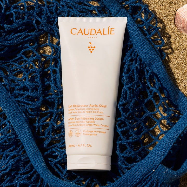 Caudalie Vinosun After-Sun Repairing Lotion 200 ml rauhoittava after sun -voide sinisellä verkkokassilla hiekalla.
