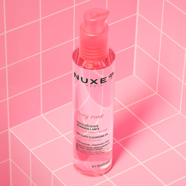 Nuxe Very Rose Cleansing Oil 150 ml puhdistusöljy vaaleanpunaisessa pumppupullossa pinkkiä laattataustaa vasten.