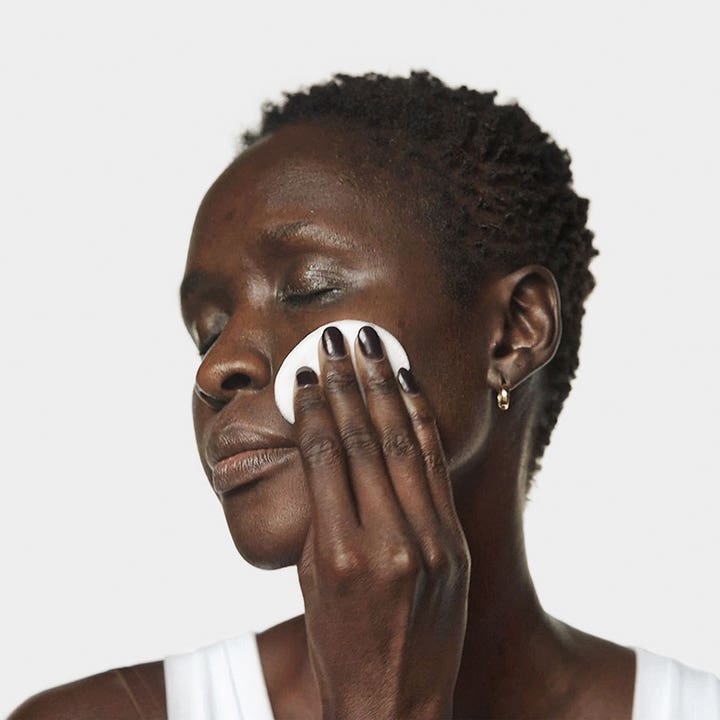 Clinique Clarifying Lotion 2 60 ml kirkastava kasvovesi jota nainen levittää iholle vanulapulla.
