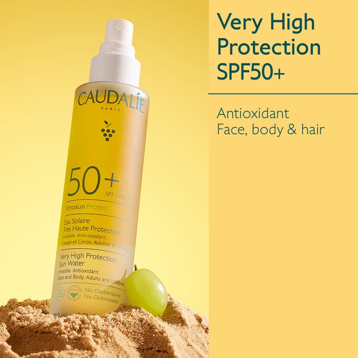 Caudalie Vinosun Very High Protection Water 150 ml SPF50+ aurinkosuojasuihke suojaa ihoa hiekassa viinirypäleen vieressä