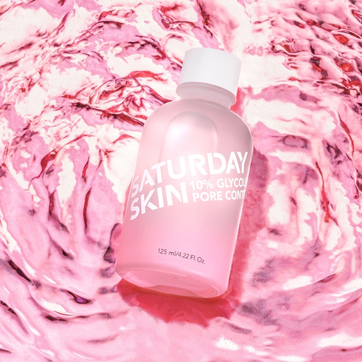 Saturday Skin Pore Clarifying Toner 125 ml kuoriva kasvovesi vaaleanpunaisessa pullossa veden päällä.