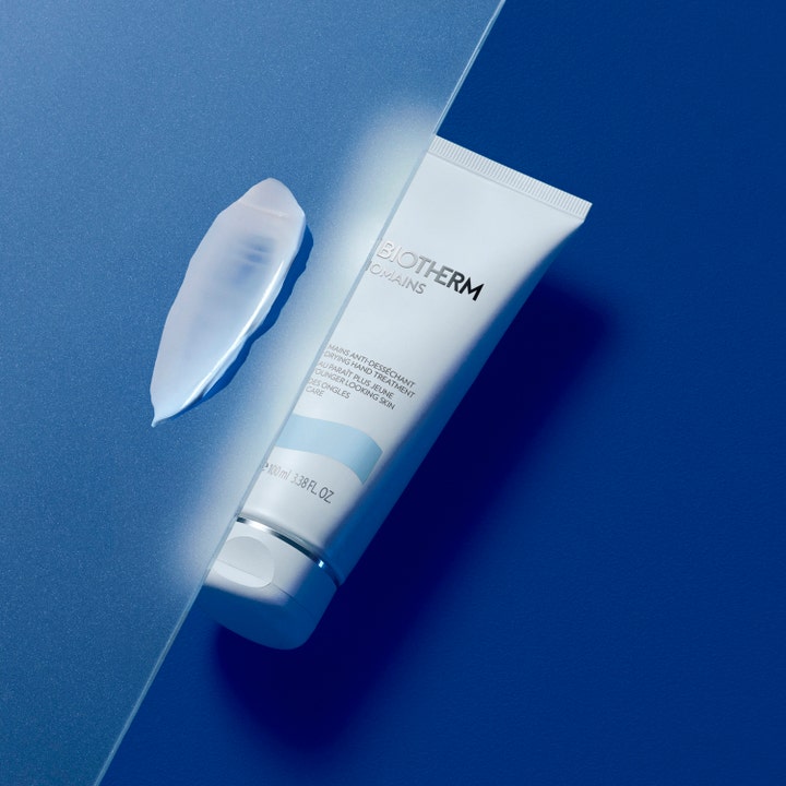 Biotherm Biomains 100 ml kosteuttava käsivoide valkoisessa tuubissa vaalean voidekoostumuksen ja sinisen taustan kera.