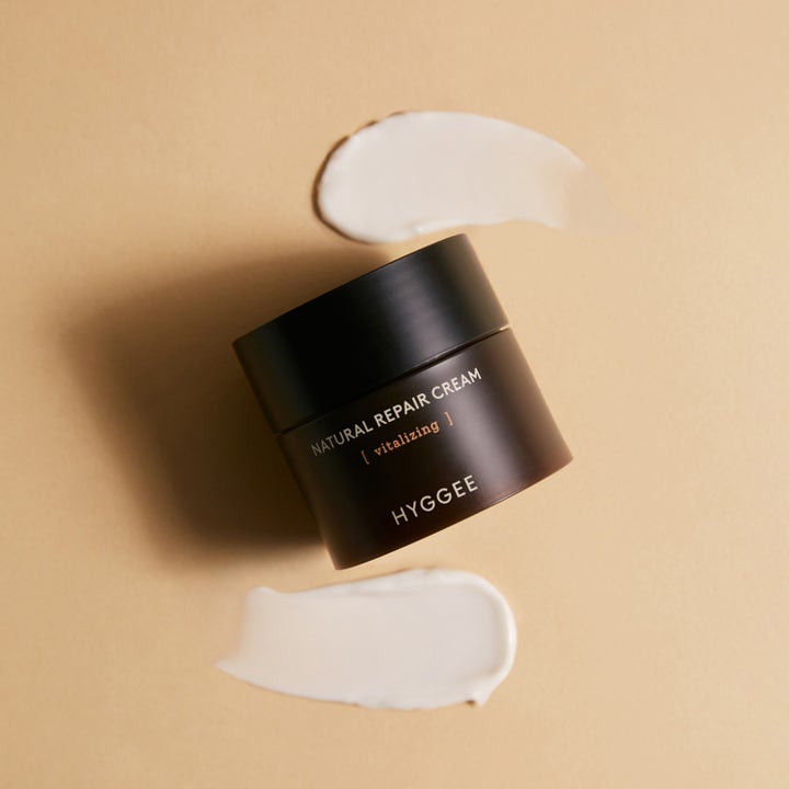 Hyggee Natural Repair Cream 50 ml elvyttävä kasvovoide tummassa purkissa vaaleilla voidepyyhkäisyillä.